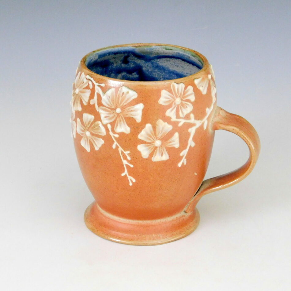 A russet colored coffee cup with floral decoration
