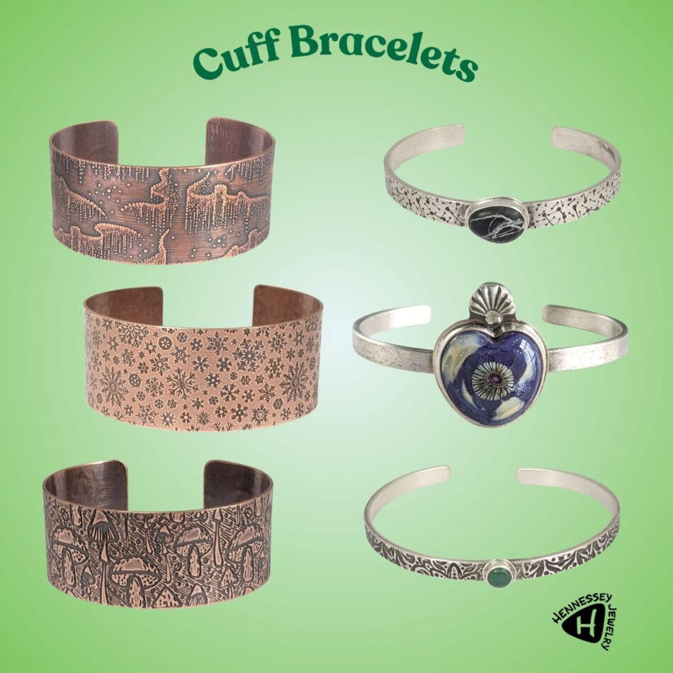 6 cuff bracelets. Three on left are copper with designs of aurora borealis, snowflakes, and mushrooms. 3 on right are sterling silver. Black and white stone on cuff with shooting star design, heart shaped stone in purple and cream, narrow patterned cuff with green gemstone