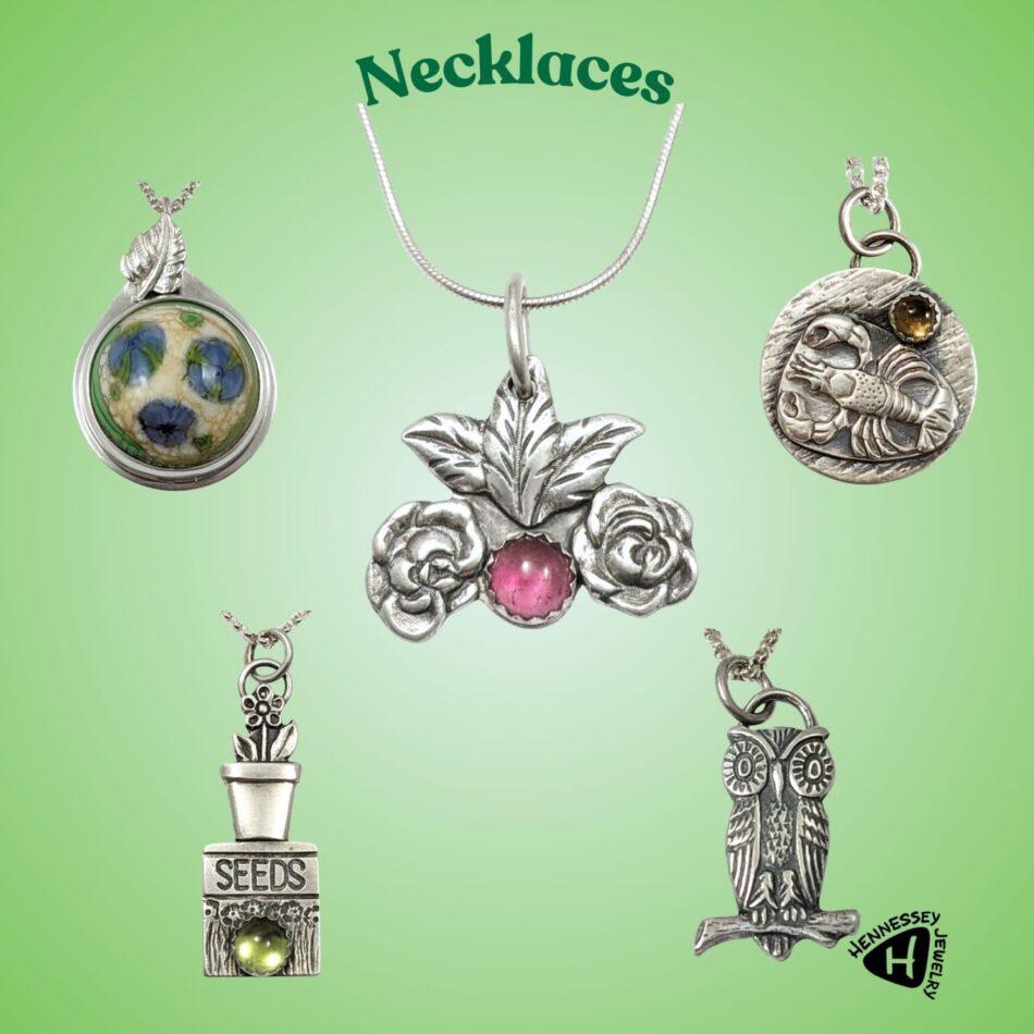 5 stelring silver necklaces. Round cream colored glass with 3 flowers, lobster with yellow gemstone, rose with pink gemstone, potted plant and seed packet with green gemstone, owl on branch.